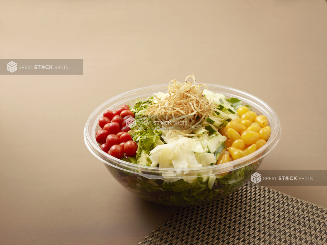 take out salad bowl with yellow and red grape tomatoes. cucumber, crispy onions and parmesan cheese