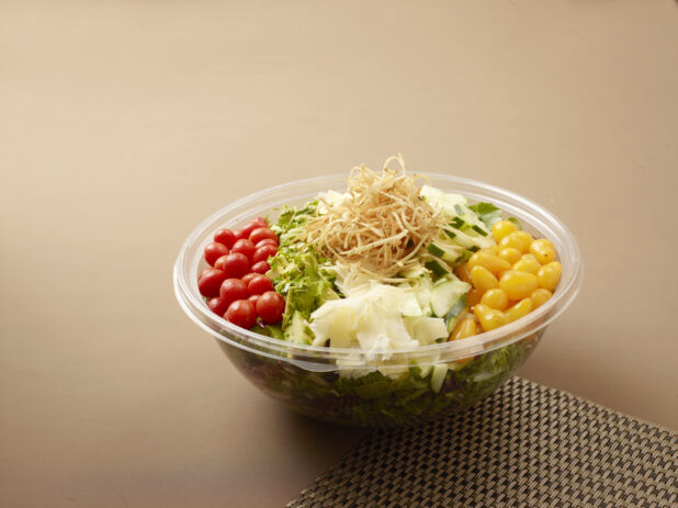take out salad bowl with yellow and red grape tomatoes. cucumber, crispy onions and parmesan cheese