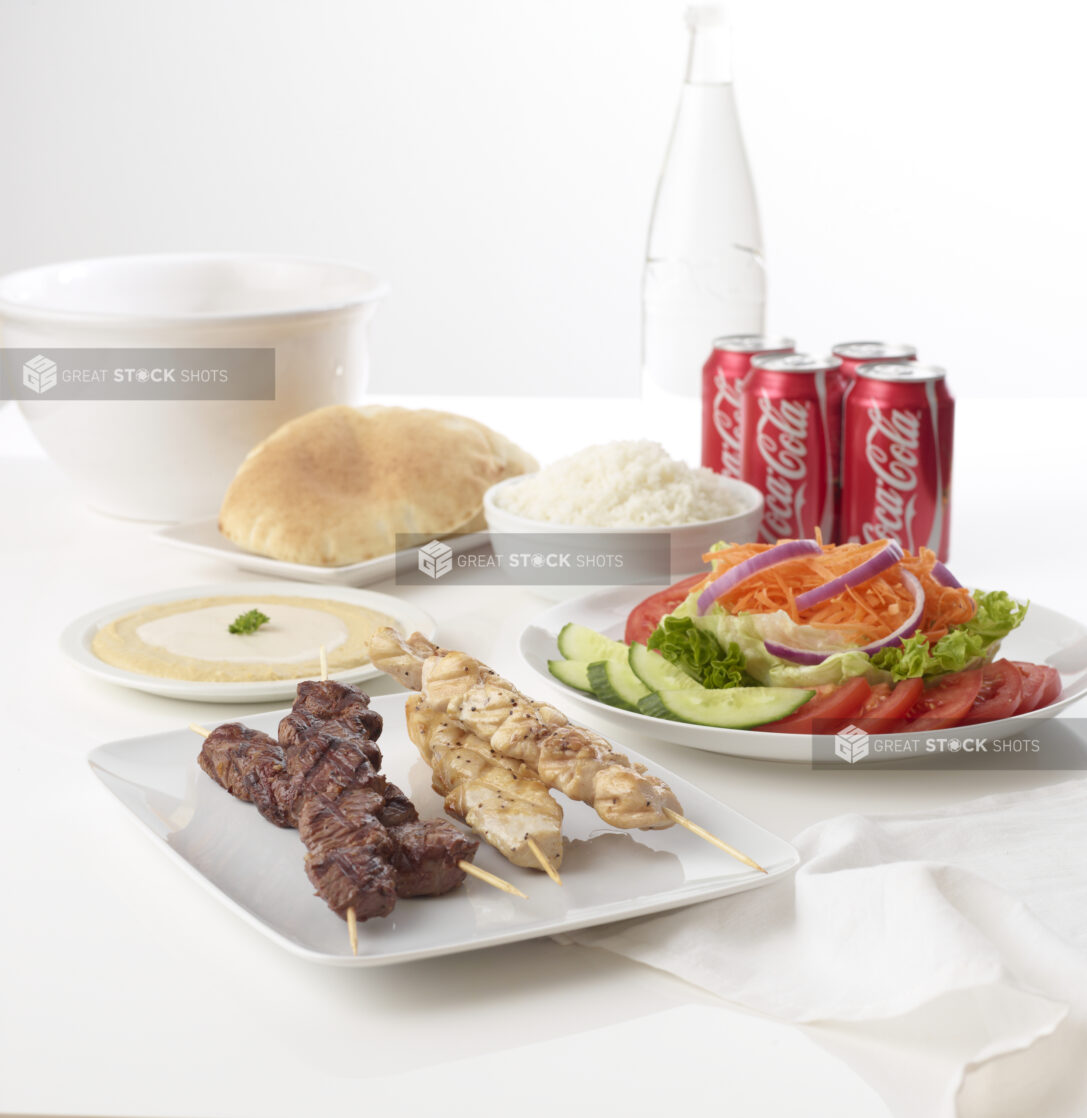 chicken and beef grilled skewer platter with pita white rice humus with tahini and salad with cucumbers tomato onions carrots and lettuce and 4 cokes