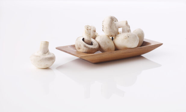 White mushrooms on a wood tray