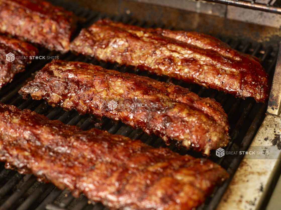 Close Up of Whole Racks of Barbecue Ribs Grilling Over an Open Flame Barbecue - Variation