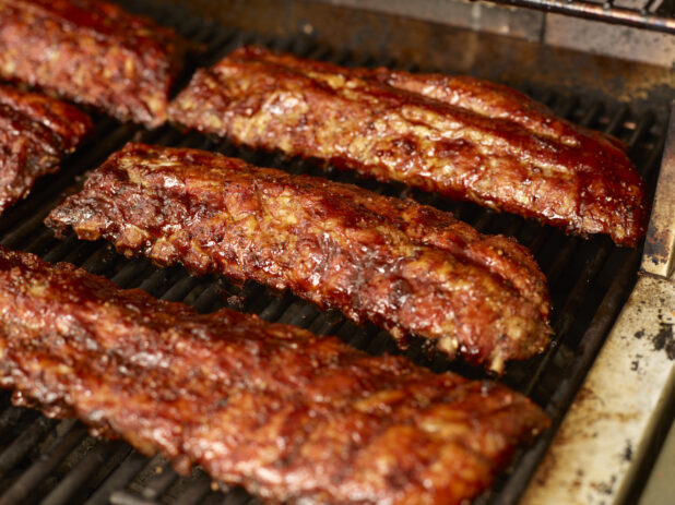 Close Up of Whole Racks of Barbecue Ribs Grilling Over an Open Flame Barbecue - Variation