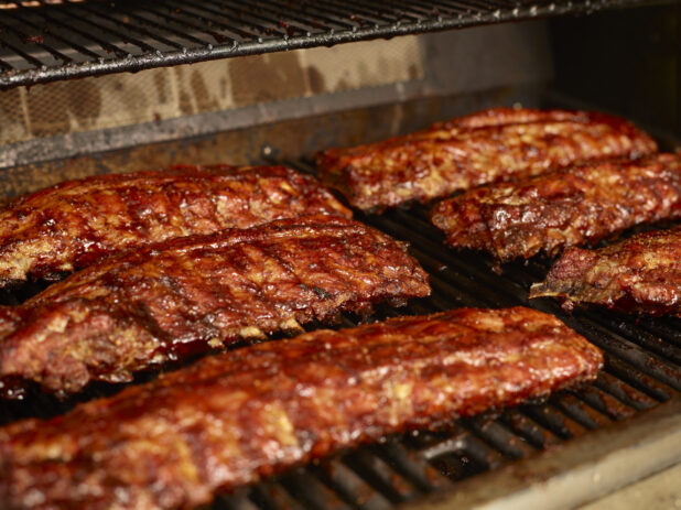 Whole Racks of Barbecue Ribs Grilling Over an Open Flame Barbecue - Variation