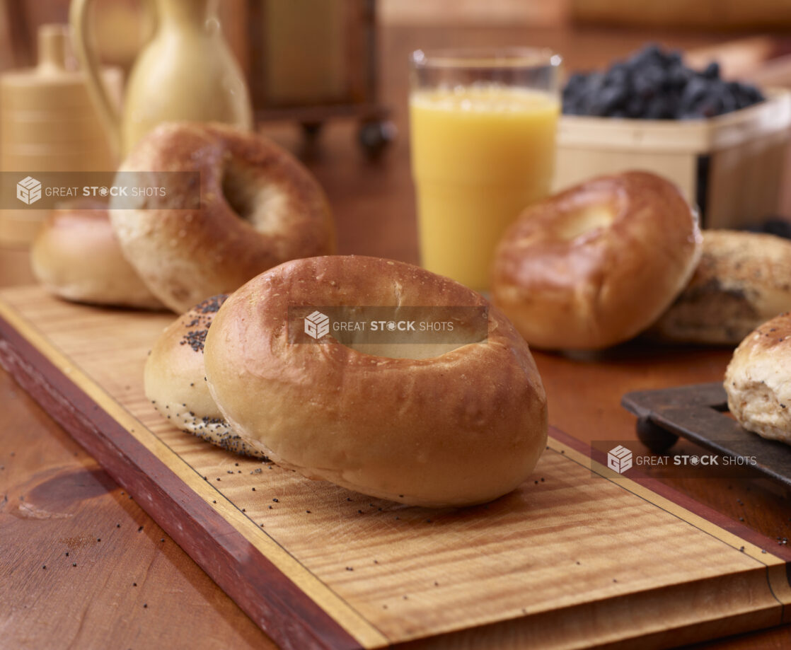 Close Up of Plain and Poppy Seed Bagels on a Wood Board in an Indoor Kitchen Setting