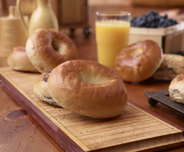 Close Up of Plain and Poppy Seed Bagels on a Wood Board in an Indoor Kitchen Setting