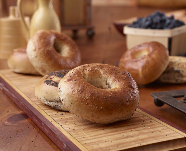 Close Up of Whole Wheat and Poppy Seed Bagels on a Wood Board in an Indoor Kitchen Setting