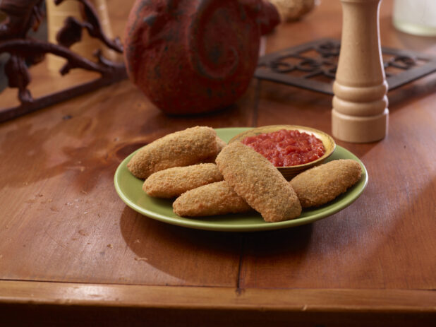 A Plate of Deep Fried Breaded Jalapeño Poppers Served with Marinara Sauce on a Wooden Table Surface in an Indoor Setting