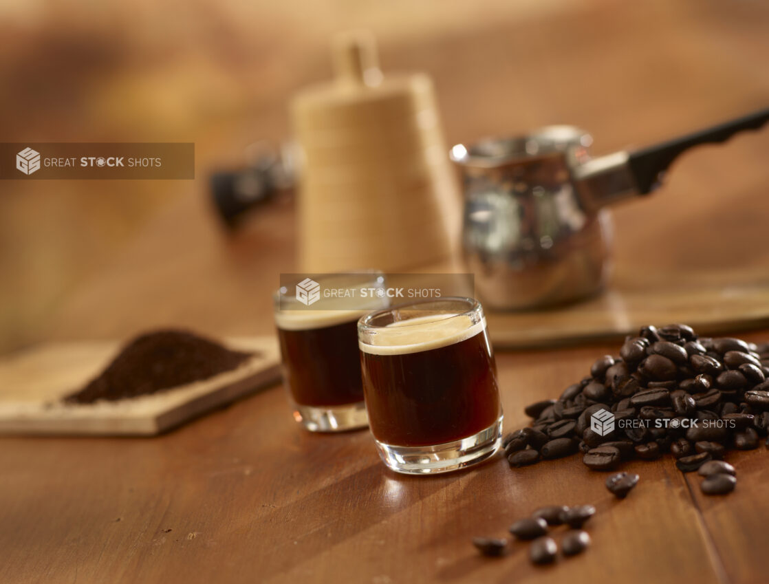 Espresso in Glass Espresso Cups with Coffee Beans and Ground Coffee on a Wooden Table in an Indoor Setting