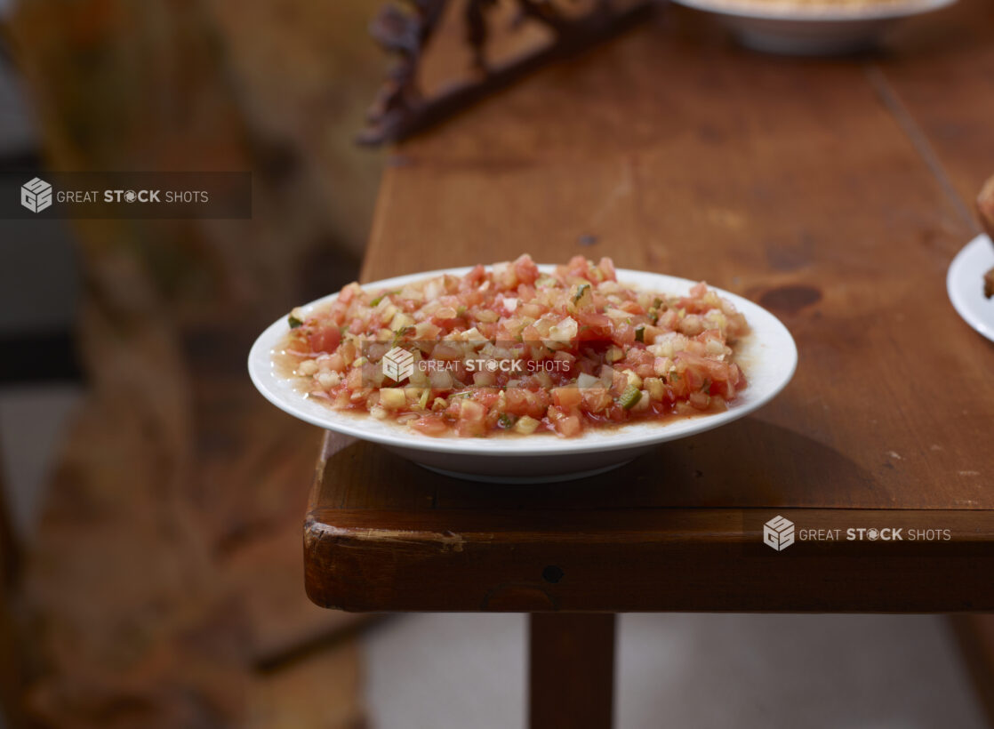 Round White Dish of Tomato Salsa on a Wooden Table in an Indoor Setting