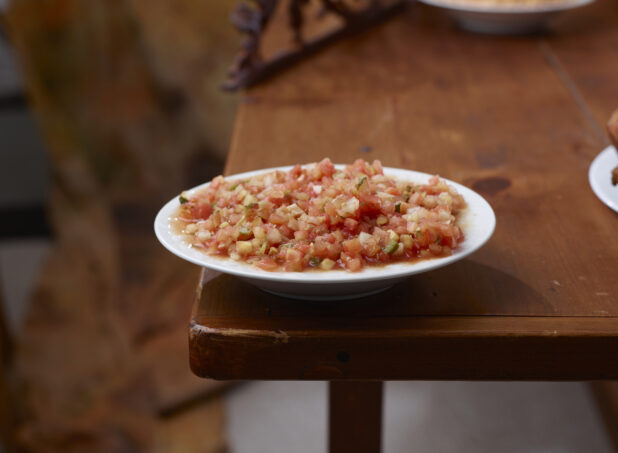 Round White Dish of Tomato Salsa on a Wooden Table in an Indoor Setting