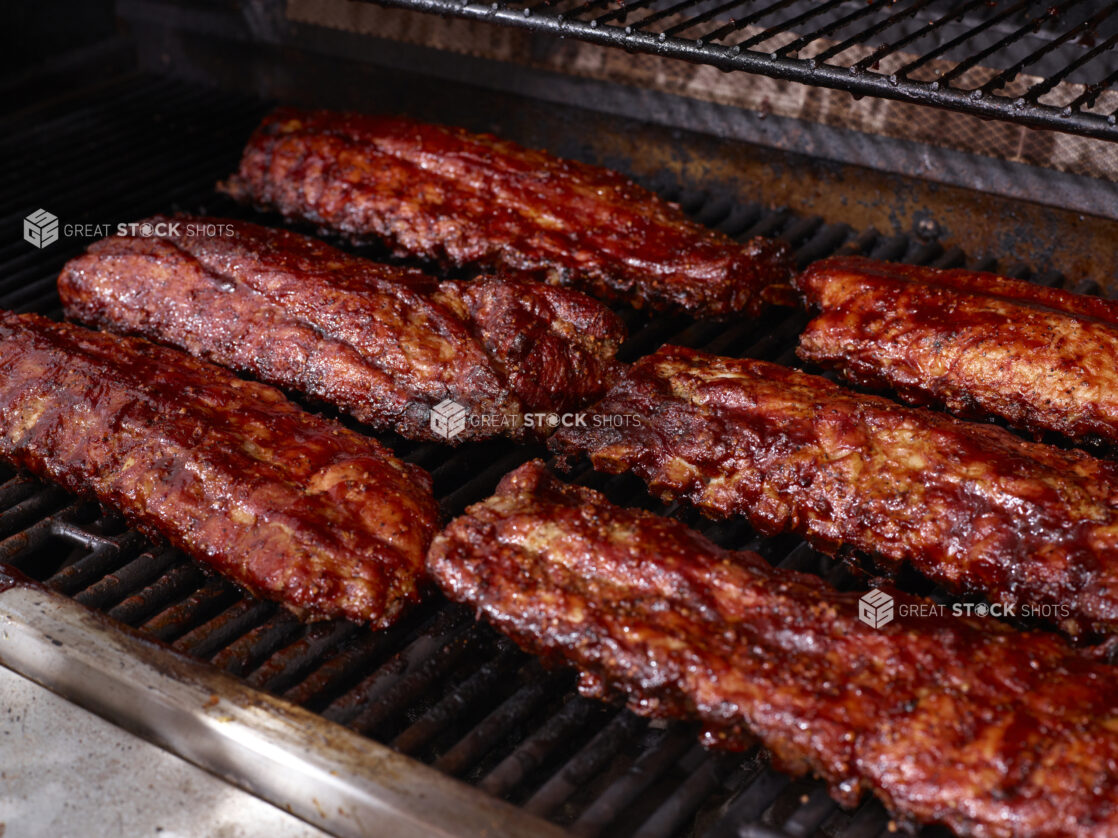 Whole Racks of Barbecue Ribs Grilling Over an Open Flame Barbecue