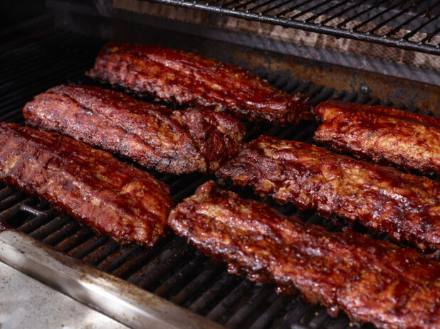Whole Racks of Barbecue Ribs Grilling Over an Open Flame Barbecue
