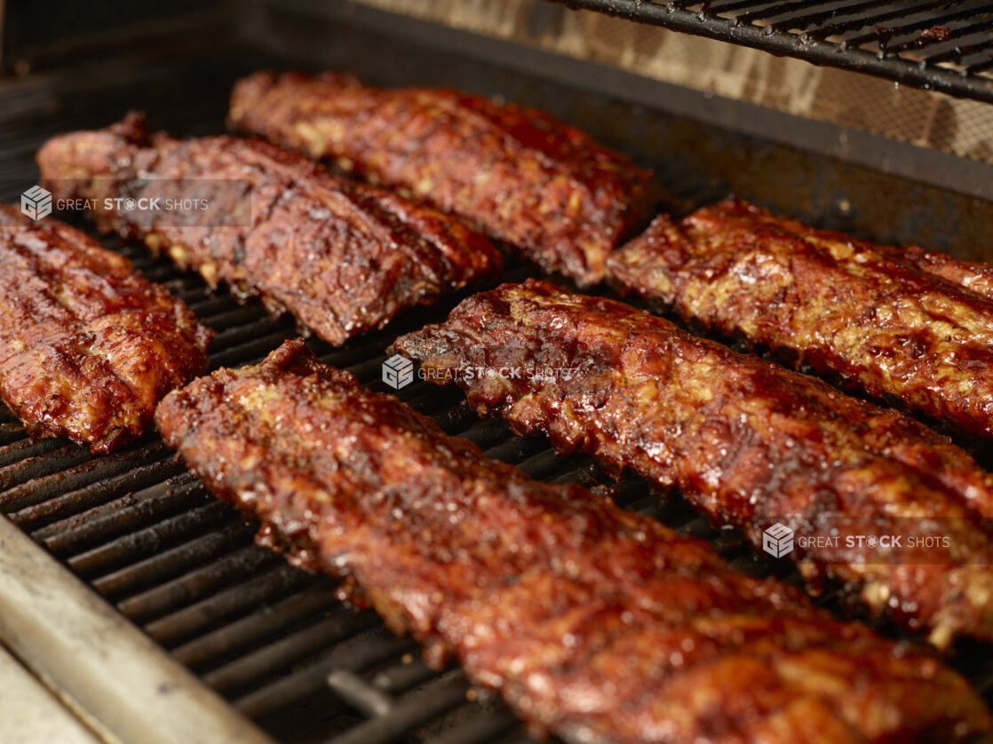 Close Up of Whole Racks of Barbecue Ribs Grilling Over an Open Flame Barbecue