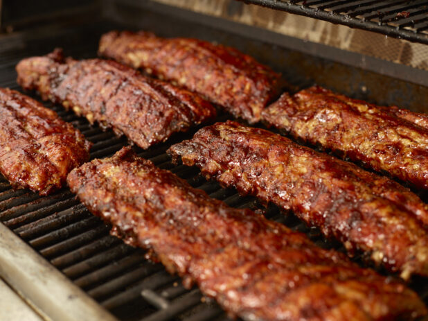 Close Up of Whole Racks of Barbecue Ribs Grilling Over an Open Flame Barbecue