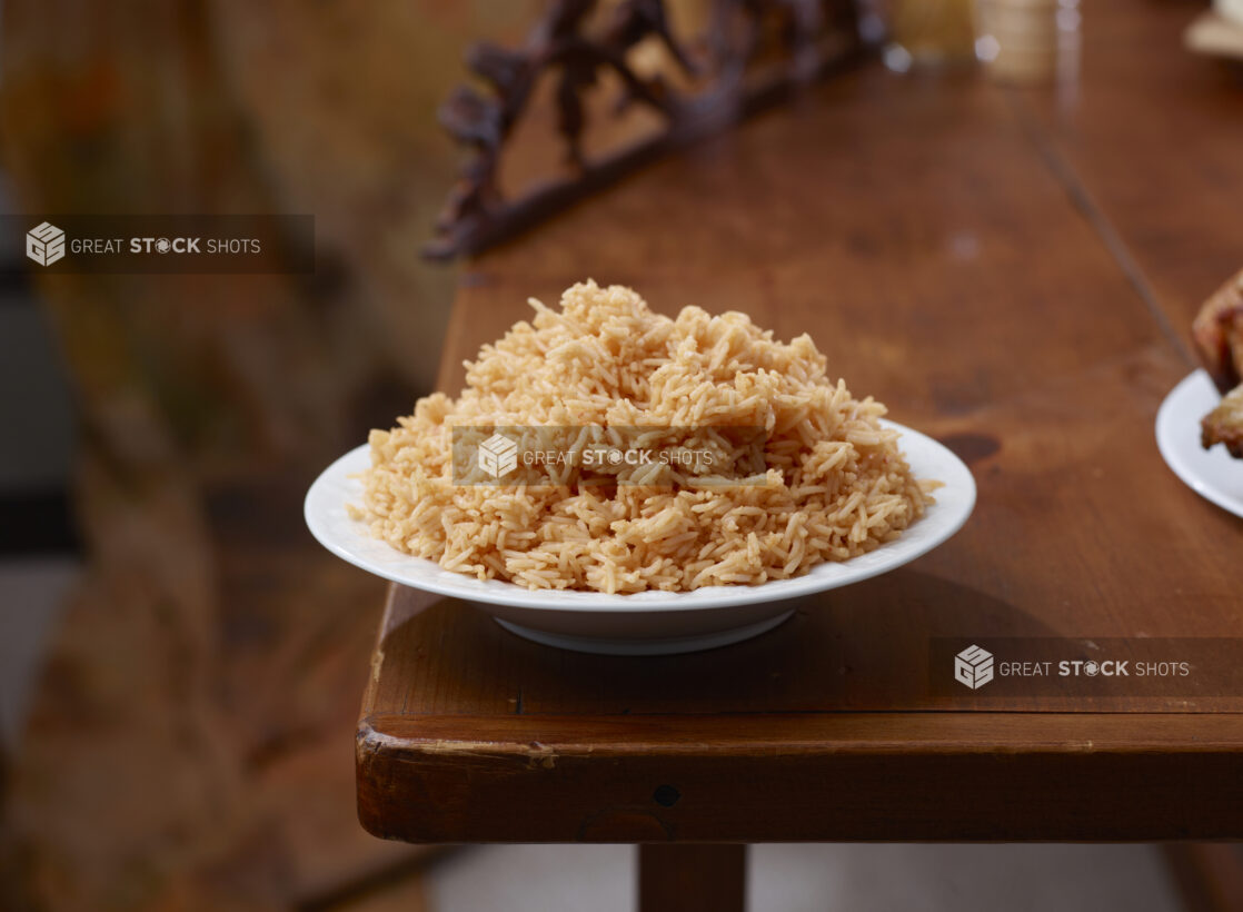 Round White Bowl of Seasoned Mexican Rice on a Wooden Table in an Indoor Setting