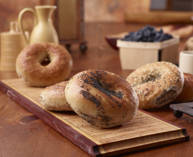 Close Up of Poppy Seed and Whole Wheat Bagels on a Wood Board in an Indoor Kitchen Setting