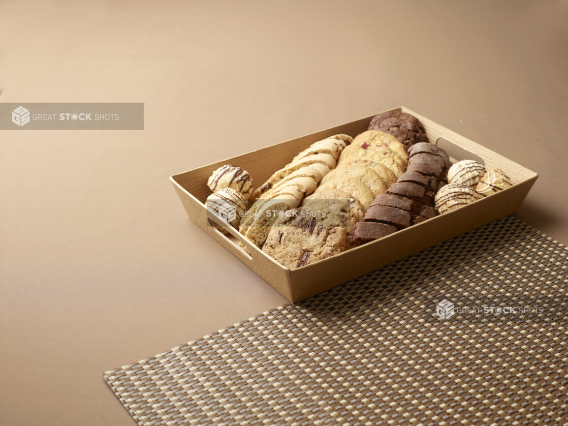 Tea and Dessert Platter with Fresh Baked Cookies, Biscotti and Cake Balls in a Wood Tray Against a Brown Background