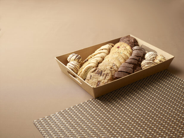 Tea and Dessert Platter with Fresh Baked Cookies, Biscotti and Cake Balls in a Wood Tray Against a Brown Background