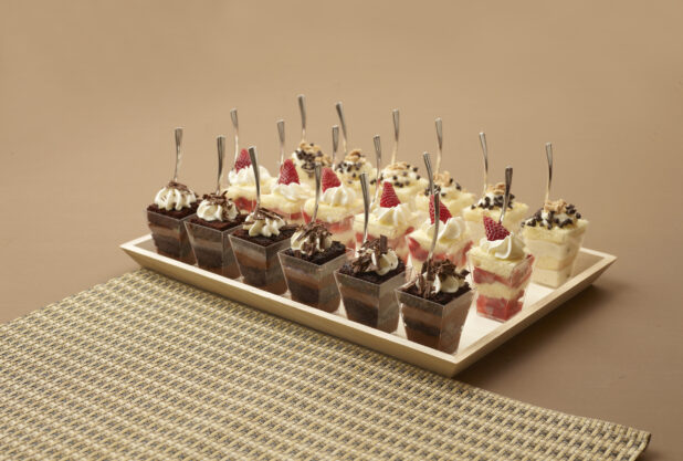 Rectangular Wood Tray with Assorted Mini Dessert Cups - Chocolate Cake, Strawberry Shortcake and Chocolate Chip Cake on a Brown Surface and Placemat - For Catering