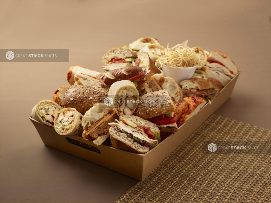 Assorted Cold Cut Sandwiches and Wraps in a Wooden Basket Tray for Catering on a Brown Background