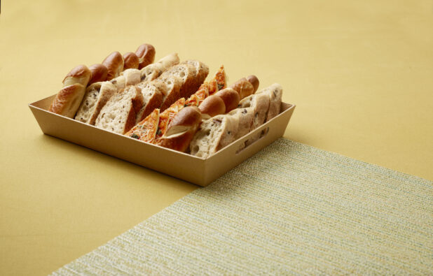 Catering Platter with Assorted Sliced Breads, Flatbreads and Focaccia on a Yellow Surface and Placemat