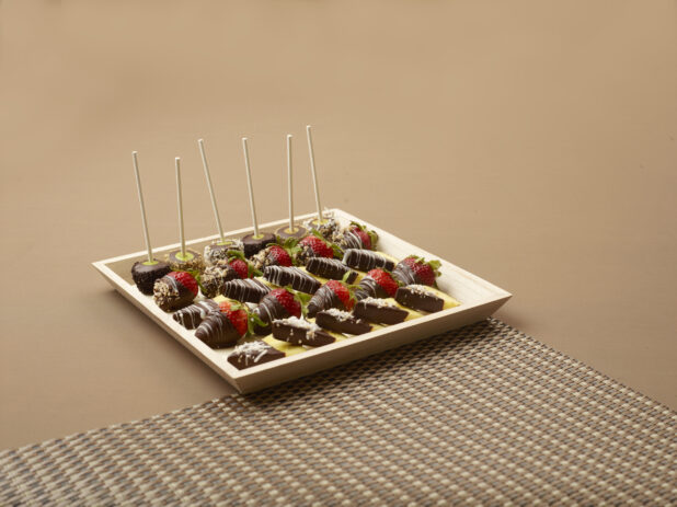 Square Wood Tray with Chocolate Covered Strawberries, Pineapple Wedges and Cake Pops on a Brown Surface and Placemat - for Catering