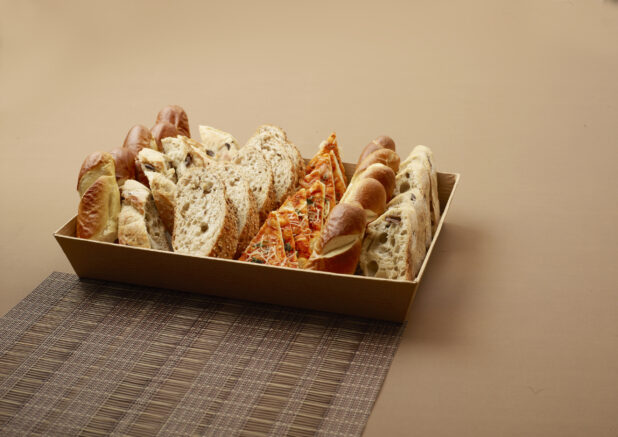 Close Up of a Catering Platter with Assorted Sliced Breads, Flatbreads and Focaccia on a Brown Surface and Placemat