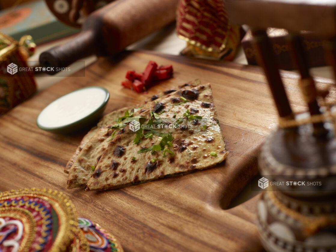 Slices of Oven-baked (Tandoor) Garlic Naan – Indian Bread on a Wooden Cutting Board in an Indoor Setting