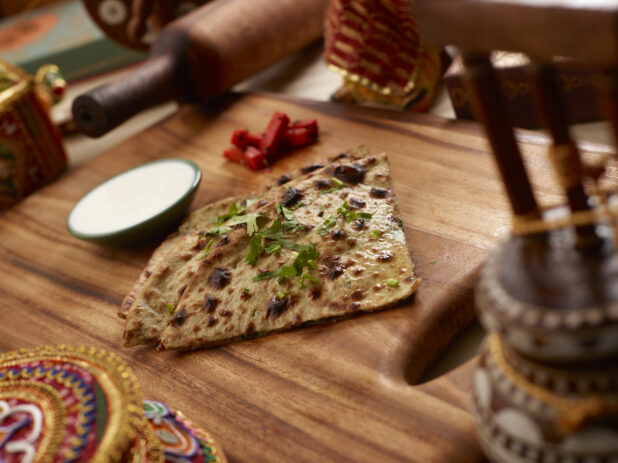 Slices of Oven-baked (Tandoor) Garlic Naan – Indian Bread on a Wooden Cutting Board in an Indoor Setting