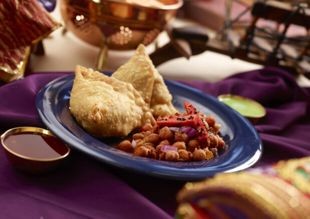 Indian Savoury Snack – Samosas – with Channa Masala Curry on a Blue Ceramic Plate on a Purple Tablecloth in an Indoor Setting