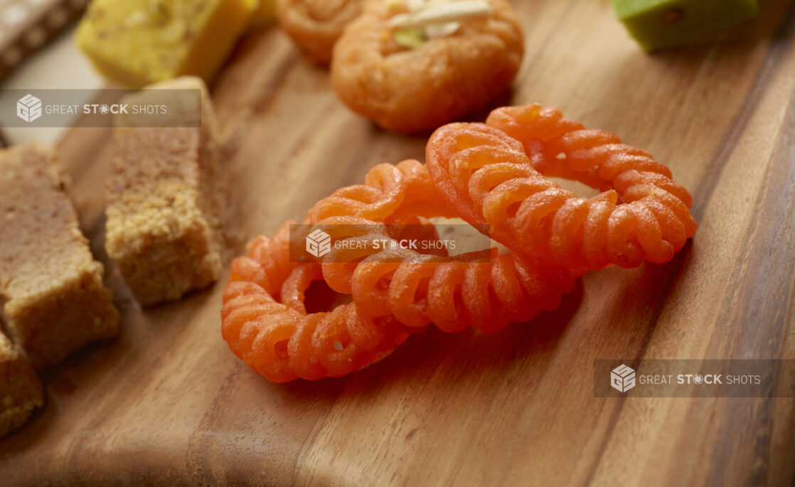 Close Up of Imarti - Indian Sweet Made of Fried Rings of Batter on a Wooden Platter with other Indian Sweets