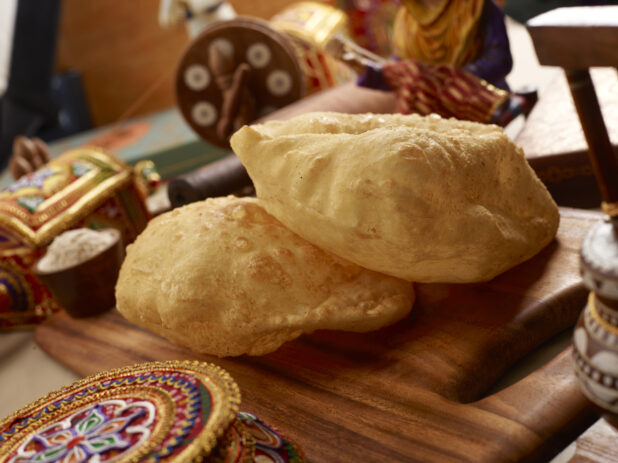 Close Up of Bhatura – Indian Deep Fried Sourdough Bread – on a Wooden Platter in an Indoor Setting