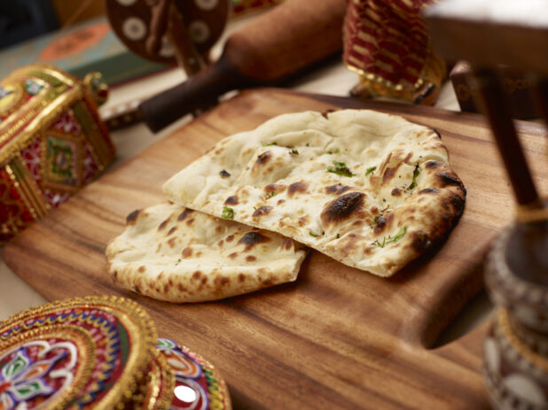 Oven-baked (Tandoor) Plain Naan – Indian Bread on a Wooden Cutting Board in an Indoor Setting