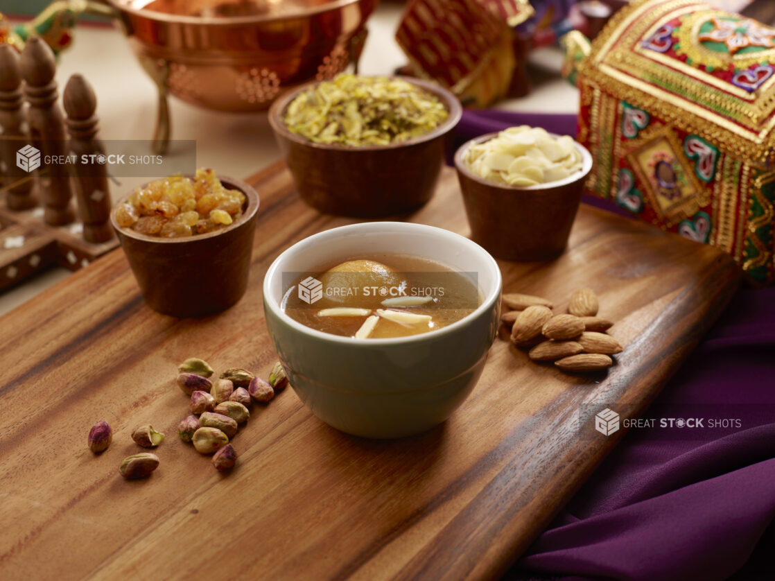 Indian Dessert Gulab Jamun – Fried Milk Dough in Sweet Sugar Syrup with Nuts and Dried Fruit Toppings on a Wooden Platter - Variation