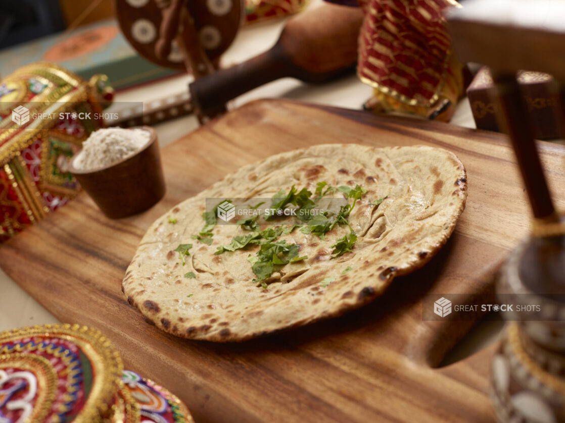 Laccha Paratha - Indian Layered Dough Bread - with chopped coriander leaves on a Wooden Cutting Board in an Indoor Setting