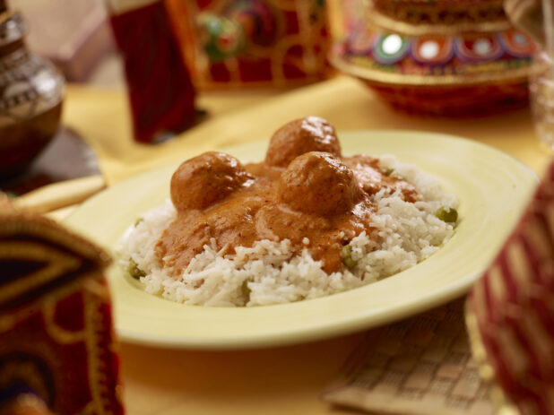 Malai Kofta - Indian Meatballs in a Tomato Gravy - over Basmati Rice in a Yellow Ceramic Dish on a Yellow Tablecloth