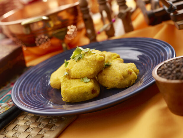 Paneer Pakora - Indian Cheese Fritters - on a Blue Ceramic Plate on an Orange Tablecloth in an Indoor Setting