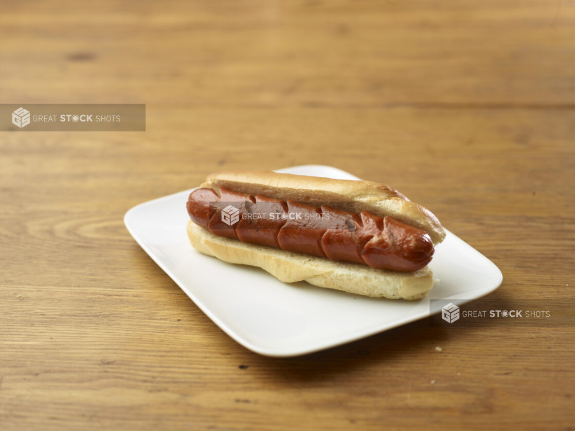 Plain Hot Dog on a Rectangular White Ceramic Dish on a Rustic Wooden Table