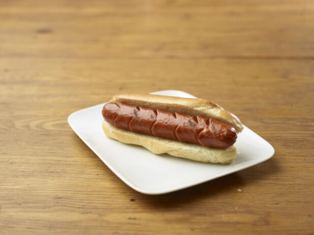 Plain Hot Dog on a Rectangular White Ceramic Dish on a Rustic Wooden Table