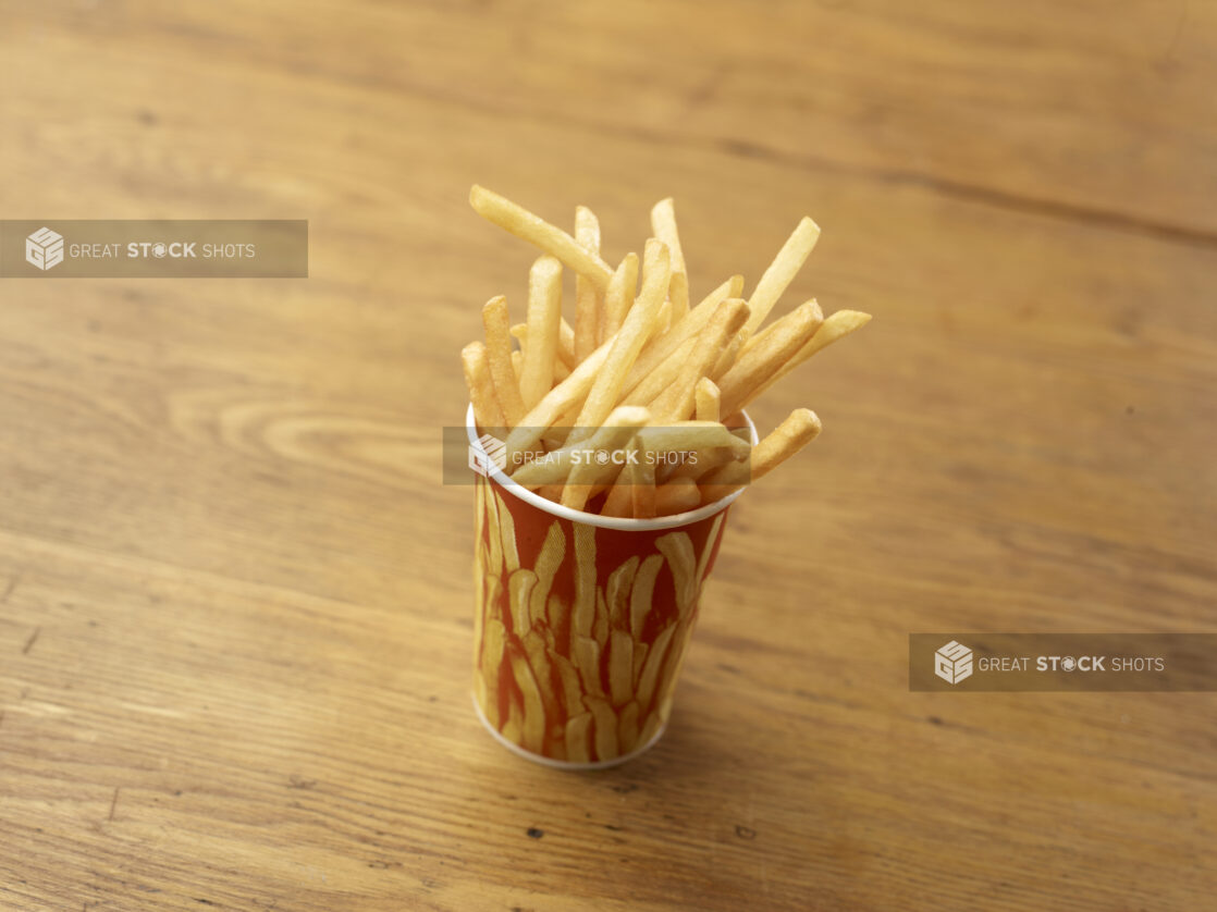 Cardboard Cup of Plain Thin-Cut French Fries on a Rustic Untreated Wood Surface