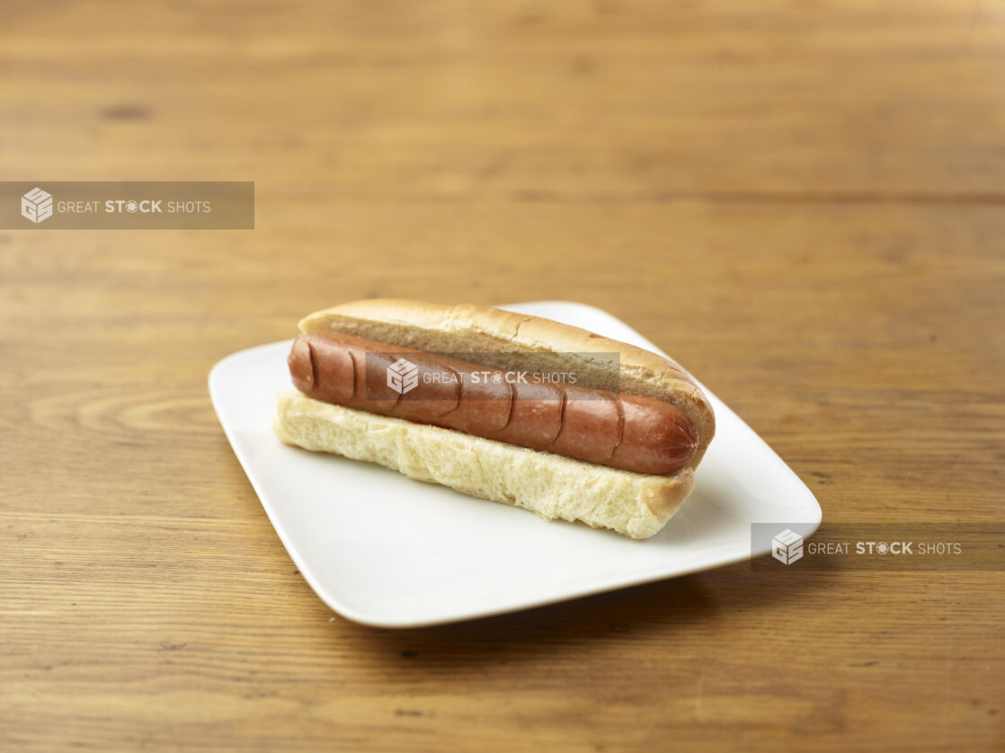 Plain Hot Dog on a Rectangular White Ceramic Dish on a Rustic Wooden Table - Variation