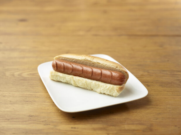 Plain Hot Dog on a Rectangular White Ceramic Dish on a Rustic Wooden Table - Variation