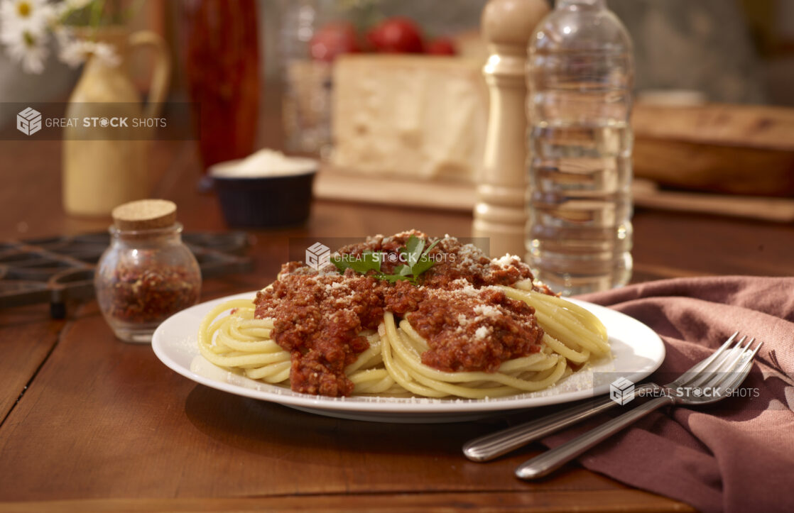 Plate of Spaghetti Bolognese with Grated Parmesan on a Restaurant Table Setting