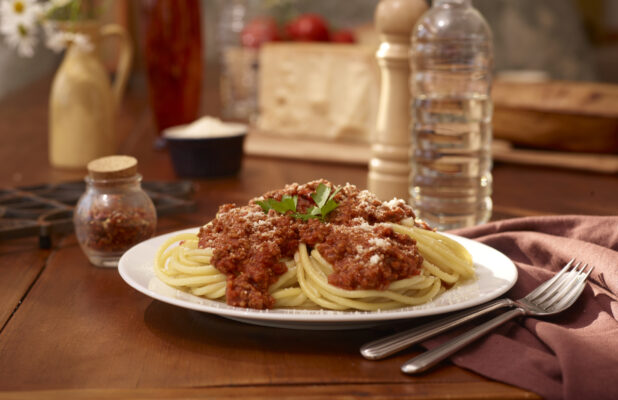 Plate of Spaghetti Bolognese with Grated Parmesan on a Restaurant Table Setting