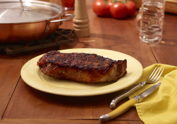 Char Grilled Steak on Yellow Dinner Plate on a Restaurant Table Setting