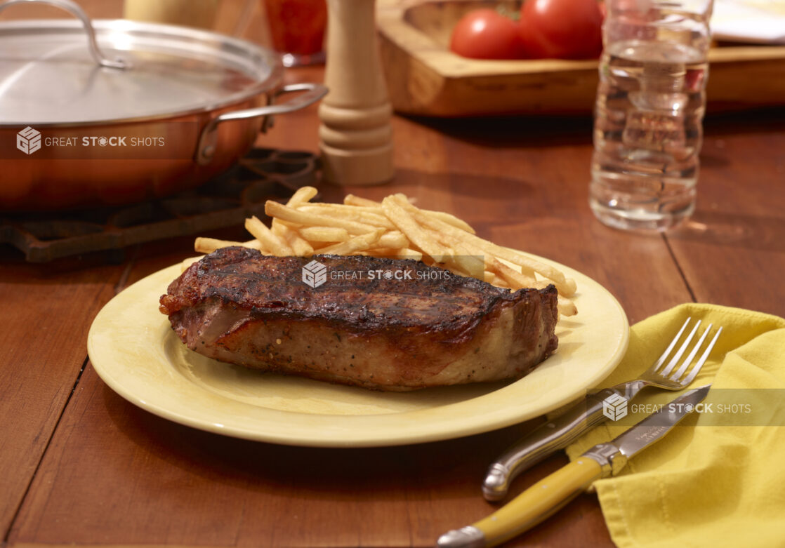 Yellow Dinner Plate with Steak and French Fries on a Restaurant Table Setting