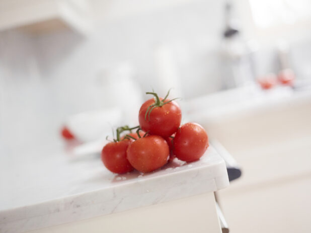 Fresh Tomatoes Stacked on Marble Counter with Bokeh Background