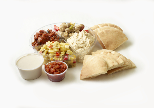 Wedges of pita bread with a variety of Middle Eastern dips and side dishes including tahini sauce and hummus