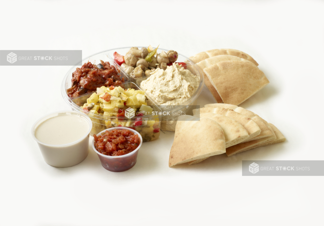 Wedges of pita bread with a variety of Middle Eastern dips and side dishes including tahini sauce and hummus