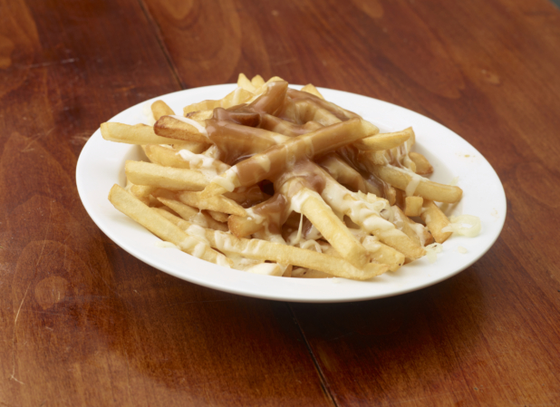 Poutine on a white plate on a wood tabletop
